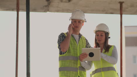 Building-in-construction-with-a-female-and-a-male-builders-constructors-engineers-walking-along-it.-Building-in-construction-with-a-female-and-a-male-engineers